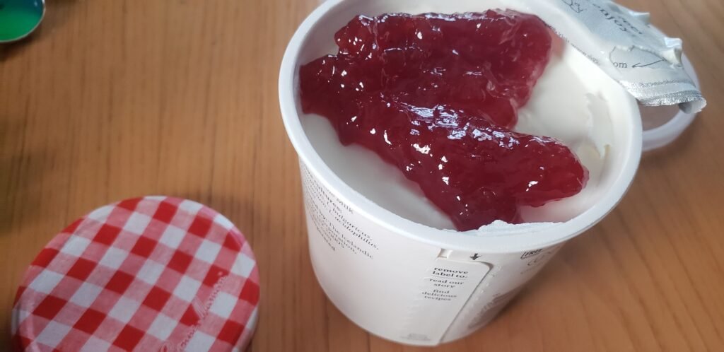 Open tub of thick plain skyr, lid peeled back, smooth and cold.