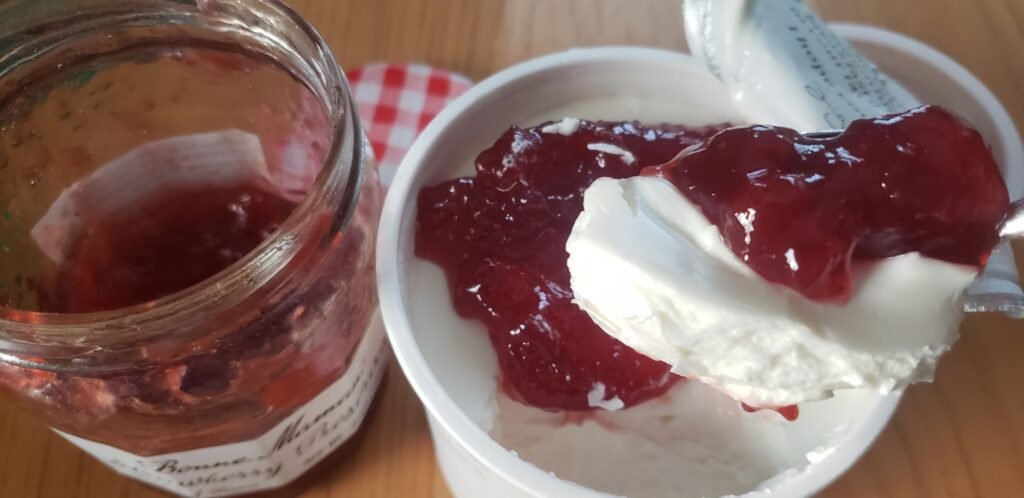 A heaping tablespoon of Bonne Maman strawberry preserves over an open tub of skyr.